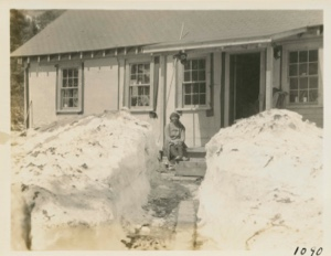 Image of Front path cut through snow bank at camp- Miriam Flowers sitting on steps